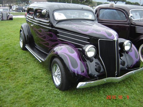 1993 Ford Bronco - A black hot rod with custom purple flame paintwork is parked on grass, with another vehicle visible behind it.