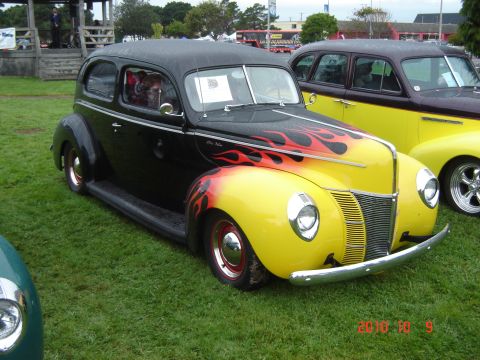 1993 Ford Bronco - A customized sedan with flame decals is displayed at an outdoor event.