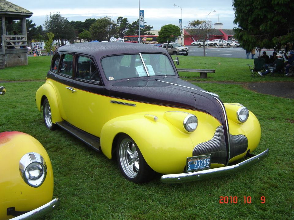 Two-tone yellow and purple sedan with chrome bumper and custom wheels parked on grass