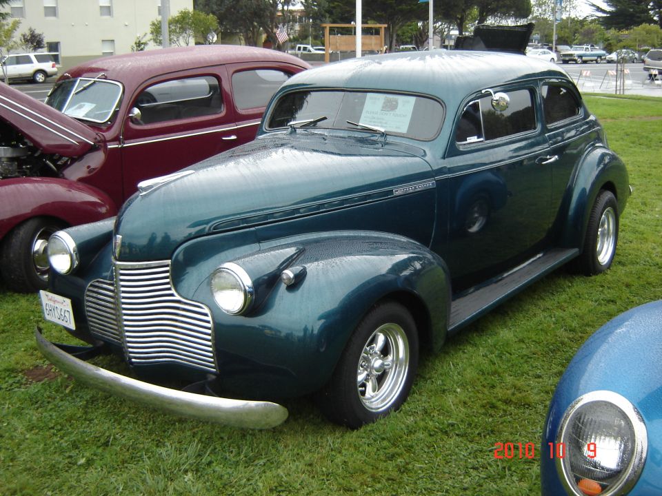 Teal sedan with chrome grille and bumper, parked on grass