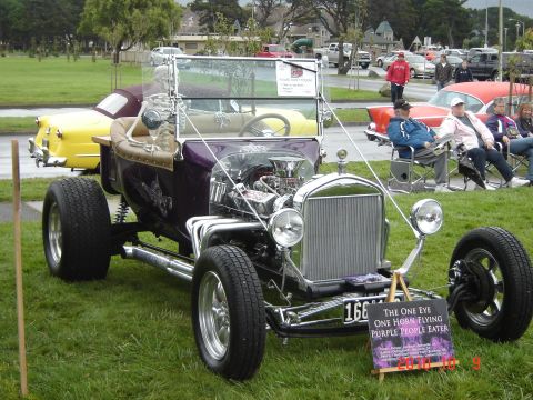 1993 Ford Bronco - Custom hot rod with a prominent V8 engine and unique purple paint job at a car show.