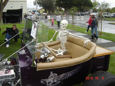 1993 Ford Bronco - A skeleton appears to be driving a vintage purple car with custom artwork, displayed at an outdoor event.