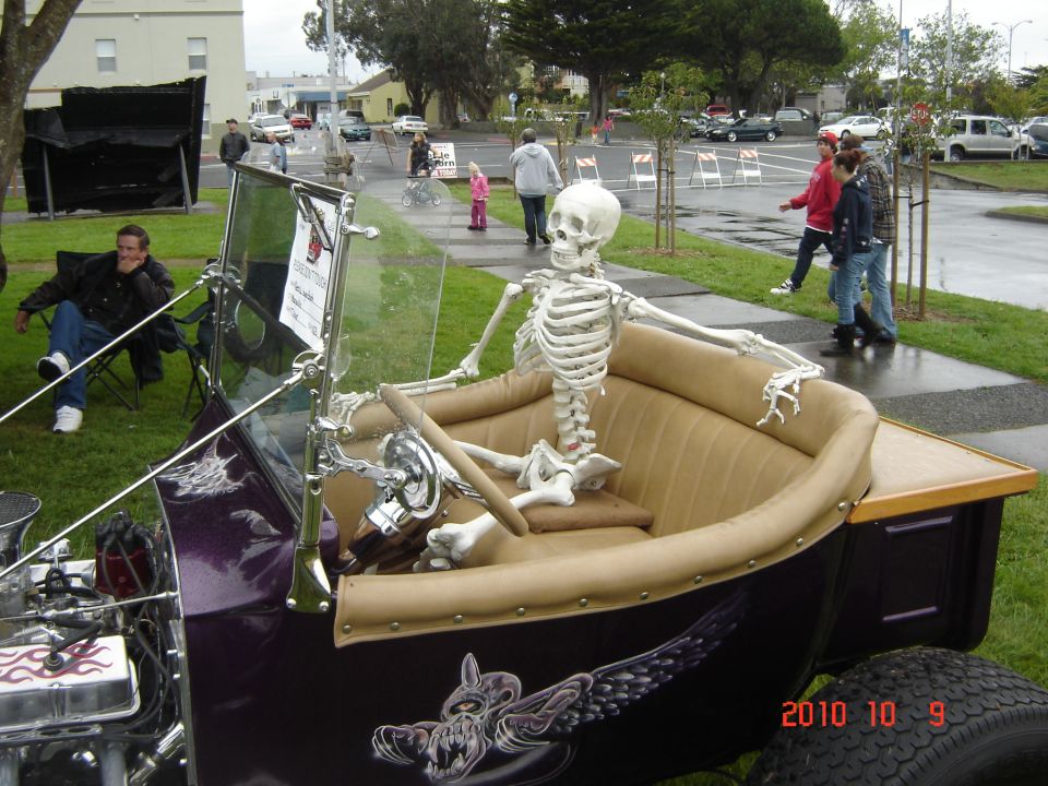Skeleton driver in a purple vintage car with custom artwork