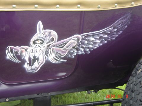1993 Ford Bronco - Airbrushed skull with wings graphic on the side of a purple vehicle.