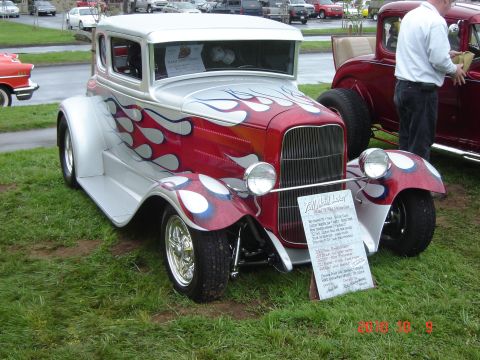 1993 Ford Bronco - A custom hot rod coupe with flame graphics is displayed on grass next to another vehicle.