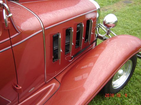 1993 Ford Bronco - Close-up of a vintage red car's hood and fender, showing chrome details and louvers, with a watermark indicating it was taken in 2010.