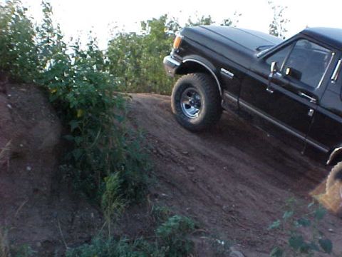 1989 Ford Bronco - Black 1989 Ford Bronco navigates an off-road dirt incline.