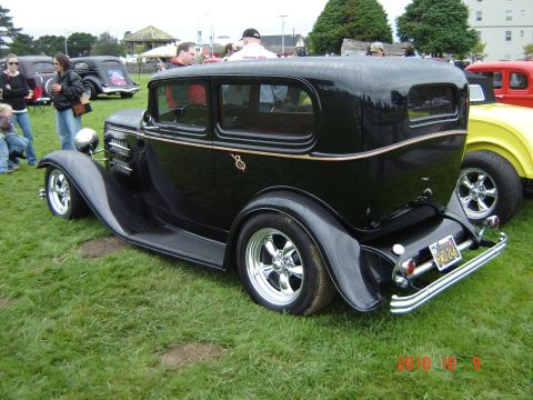 1993 Ford Bronco - A classic black sedan with custom wheels is displayed at an outdoor car show.