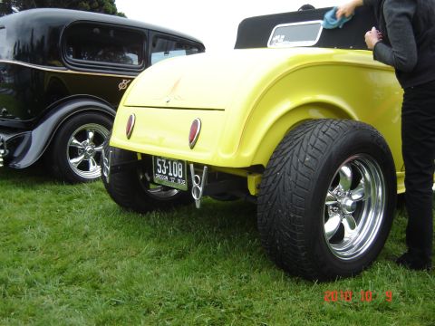 1993 Ford Bronco - Two classic cars, a yellow hot rod and a black sedan, are parked on grass. The hot rod's license plate indicates it is from 1932.