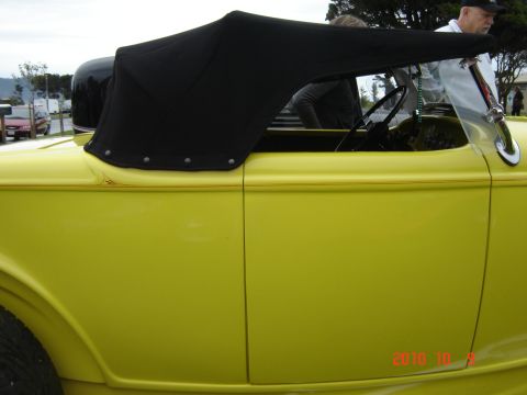 1993 Ford Bronco - A yellow convertible with its black top up is shown from the side, with people visible inside.