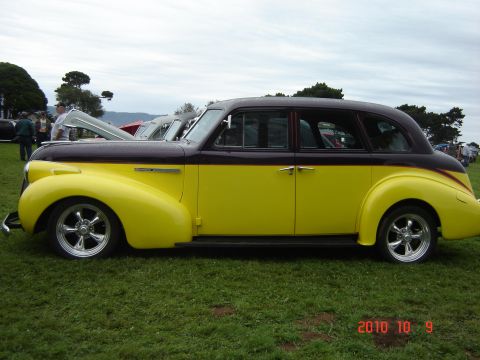 1993 Ford Bronco - A two-tone sedan with custom wheels is parked on a grassy field at an outdoor event.