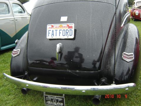 1993 Ford Bronco - Black car with 'FAT FORD' license plate, parked on grass with other vehicles nearby.