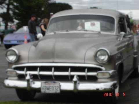 1993 Ford Bronco - A classic silver sedan is parked at an outdoor event, with another vehicle visible in the background.