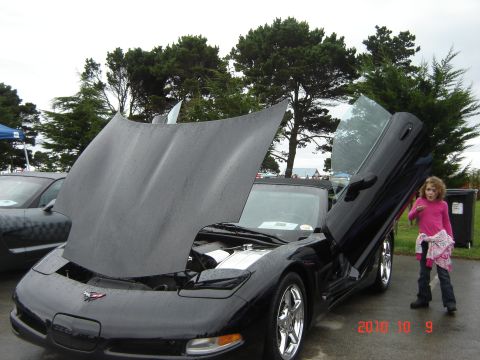1993 Ford Bronco - Black sports car with butterfly doors open, a child stands next to it. Date stamp shows 2010-10-09.