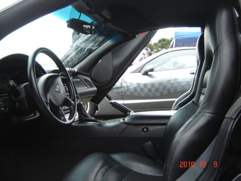 1993 Ford Bronco - The interior of a C5 Corvette is shown, with a glimpse of another vehicle parked alongside.