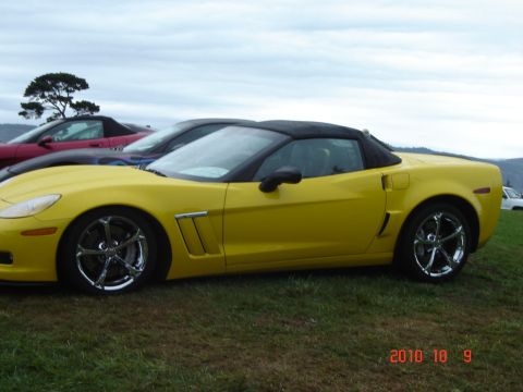 1993 Ford Bronco - Side view of a yellow convertible sports car with a black top, parked outdoors.