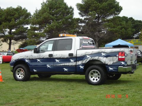 1993 Ford Bronco - A customized pickup truck with patriotic paint is parked on grass with other vehicles nearby.