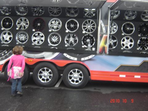 1993 Ford Bronco - A trailer is shown with many wheels displayed on its side, while a young child observes.
