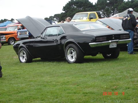 1993 Ford Bronco - A black coupe with its hood open is displayed on a grassy field alongside other vehicles.