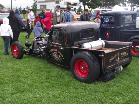 1993 Ford Bronco - A modified pickup truck with custom paint and a visible fuel tank is parked on grass.
