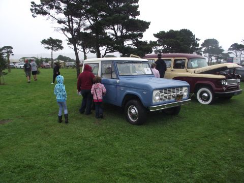 1993 Ford Bronco - Two classic trucks displayed on a grassy field at an outdoor event.