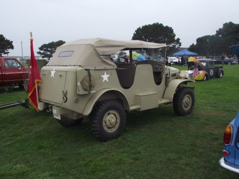 1993 Ford Bronco - Military-style jeep with a canvas top parked on grass at an outdoor event.