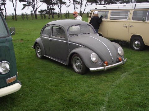 1993 Ford Bronco - A classic Volkswagen Beetle is parked on a grassy field with other vehicles nearby.