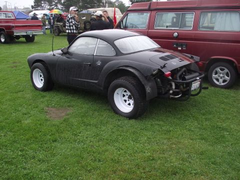 1993 Ford Bronco - A heavily modified Volkswagen Karmann Ghia with off-road tires and a custom roll cage is displayed at an outdoor event.