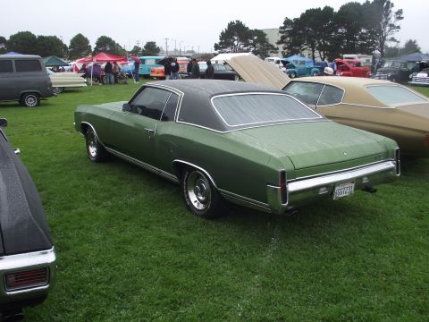 1993 Ford Bronco - A green coupe with a black vinyl top is parked on a grassy field, with other vehicles and tents visible in the background.