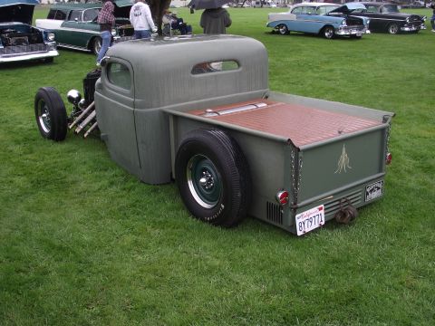 1993 Ford Bronco - A custom hot rod pickup truck is parked on a grassy field with other vintage vehicles in the background.