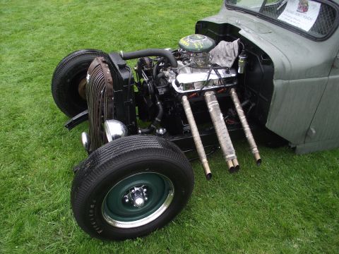 1993 Ford Bronco - Custom hot rod truck's engine bay and front wheel assembly are displayed on a grassy field.