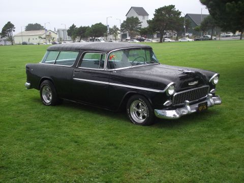 1993 Ford Bronco - A classic black Chevrolet Nomad station wagon is parked on a grassy field under an overcast sky.