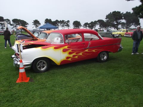 1993 Ford Bronco - A classic 1957 Chevrolet Bel Air hot rod with custom flame paint is displayed at an outdoor car show.