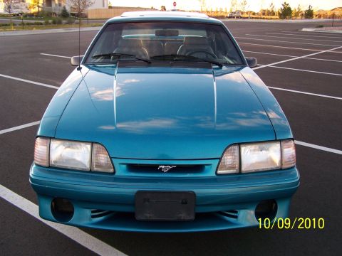1995 Ford Bronco - This teal Ford Mustang features a distinctive grille emblem and headlights, captured from a frontal perspective.