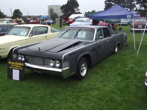 1993 Ford Bronco - A dark gray Lincoln Continental is displayed at an outdoor event with other vehicles and tents.