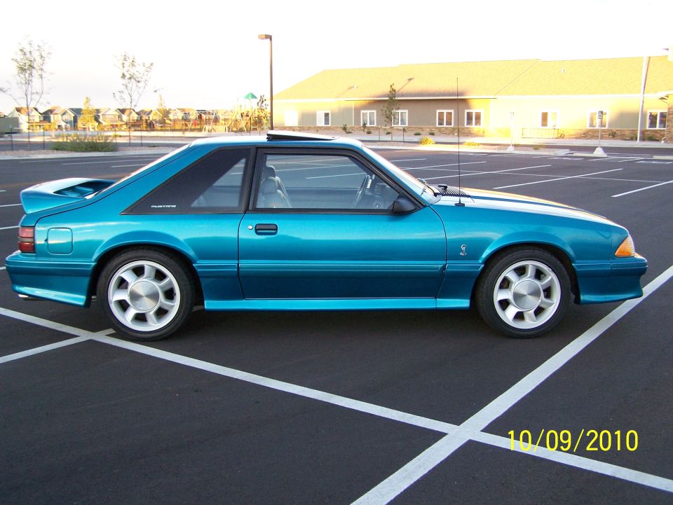 Teal coupe with a rear spoiler parked in a lot