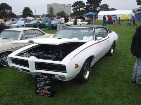 1993 Ford Bronco - White 1969 Pontiac GTO at a car show, hood open, with a descriptive sign in front.