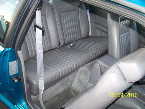 1995 Ford Bronco - The interior of a car shows the rear seating area, including gray leather seats and seatbelts, with a date stamp and website logo in the co…