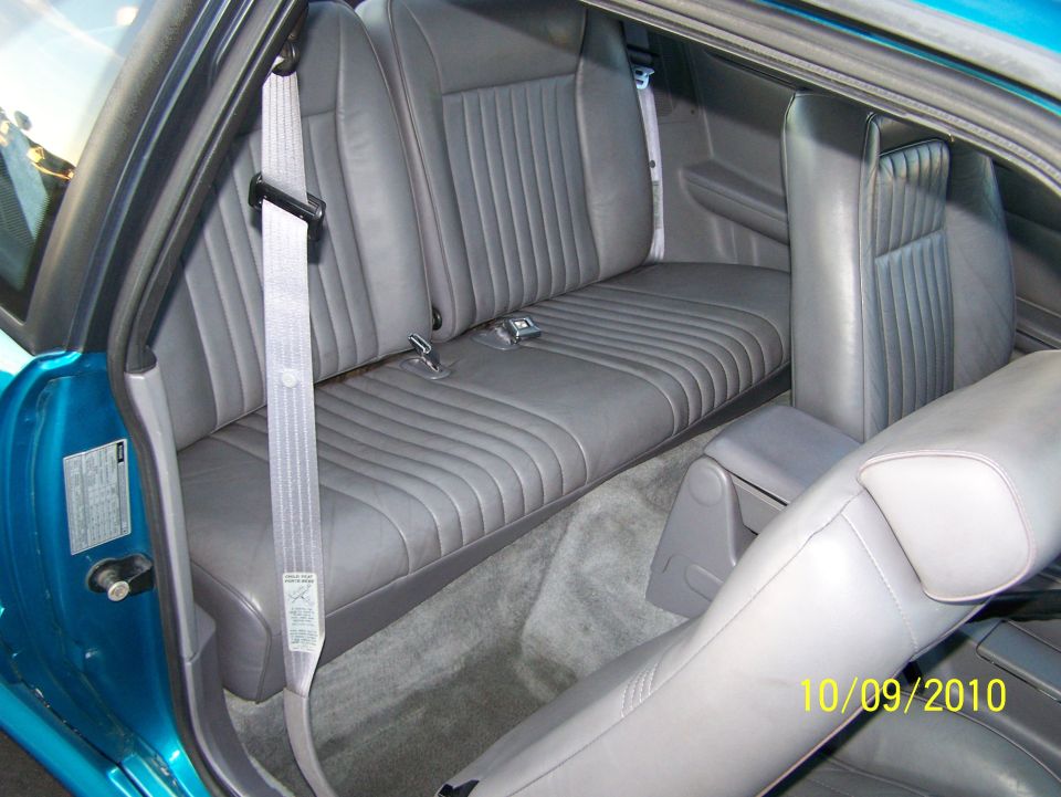 Back seat and center console of a car. Gray leather seats with seatbelts. Date stamp 10/09/2010 and Supermotors.net logo visible