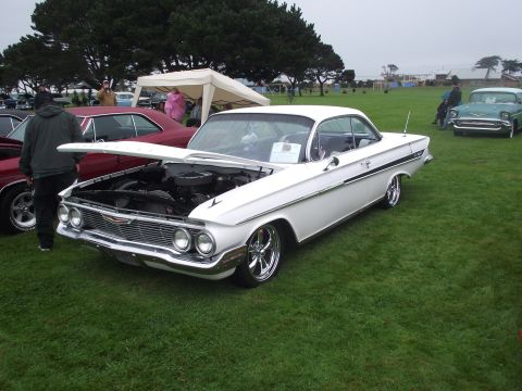 1993 Ford Bronco - A white 1961 Chevrolet Impala coupe is displayed with its hood open at an outdoor car show.