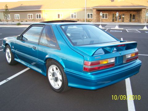 1995 Ford Bronco - A teal Ford Mustang coupe is viewed from the rear three-quarter angle in a parking lot.