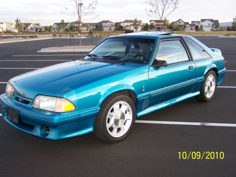 1995 Ford Bronco - Teal coupe with aftermarket wheels parked in a lot.