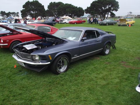 1993 Ford Bronco - A dark blue 1970 Ford Mustang coupe is displayed with its hood open at an outdoor car show.
