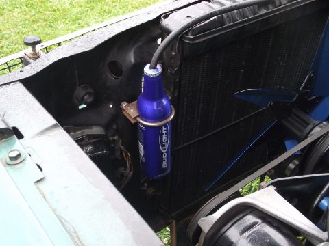 1993 Ford Bronco - A Bud Light aluminum bottle repurposed as a coolant overflow tank, clamped to the inner fender beside the radiator with a hose run into its…