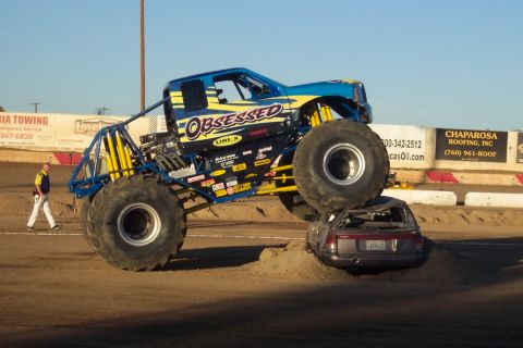 1995 Ford Bronco - A monster truck is shown crushing a sedan during an event.
