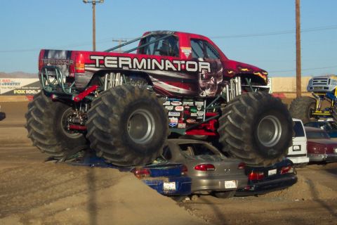 1995 Ford Bronco - The 'Terminator' monster truck dominates the scene, crushing two cars beneath its massive tires.