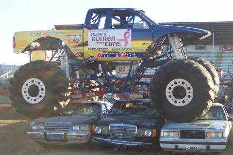 1995 Ford Bronco - A monster truck is positioned over multiple crushed cars, with sponsor logos visible on its side.