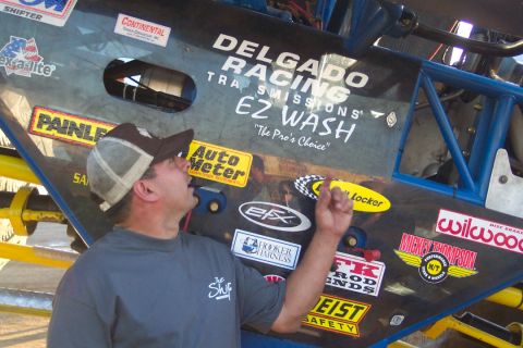 1995 Ford Bronco - A man examines the extensive sponsor decals adorning a custom off-road vehicle.
