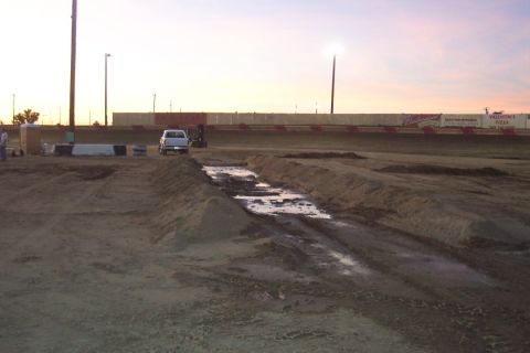 1995 Ford Bronco - A white pickup truck is parked on a dirt track with a muddy section in the foreground.