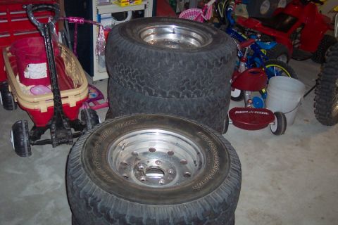 1995 Ford Bronco - Tires are stacked in a garage setting, obscuring any view of a vehicle.